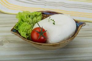 mozzarella i en skål på trä- bakgrund foto