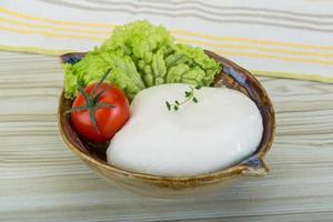 mozzarella i en skål på trä- bakgrund foto