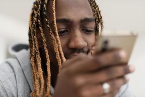 afro kille användningar en cell telefon och bläddrar social media under en pandemi foto
