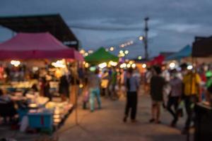 suddig bild av natt marknadsföra festival människor gående på väg med ljus bokeh för bakgrund. foto