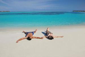 Lycklig ung par njuter sommar på strand foto