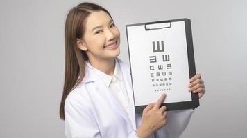 ung kvinna ögonläkare med glasögon innehav öga Diagram över blå bakgrund studio, sjukvård begrepp foto