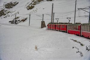 röd tåg i de snö i swiss alps foto