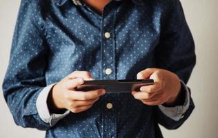 pojke spelar spel på smartphones, pojke hand som håller en smartphone foto