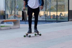 begreppet ung, snabb och mobil chef. rolig affärsman på skateboard i svart kostym. foto