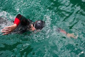 triathlon idrottare simmar på sjön bär våtdräkt foto