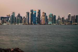 doha qatar skyline på natten som visar skyskrapor ljus som reflekteras i den arabiska viken foto