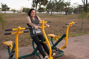 mogen kvinna tränar och försöker komma i form på en utomhus fitnesspark foto