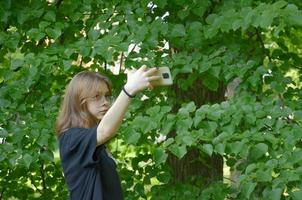 en tjej tar bilder av sig själv på sin telefon nära träden foto