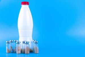 flaskor, ampuller med torr probiotika, bifidobakterier och en flaska med mjölk på blå bakgrund. kopieringsutrymme. foto