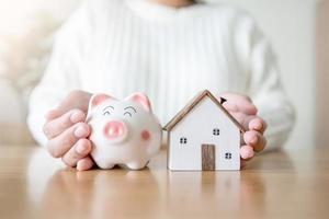 kvinna med spargris och framtida hus koncept för att spara och låna pengar till huset. att hyra eller köpa nytt hus med att spara pengar i spargris. foto