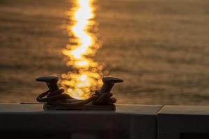 båt pollare detalj på solnedgång gul vatten bakgrund foto