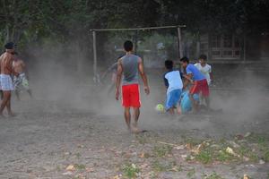 gili asahan, indonesien - augusti, 22 2016 - Pojkar är spelar fotboll på solnedgång på en handflatan träd fält nära de strand foto