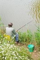 fiskare fångster en fisk från flodbank foto