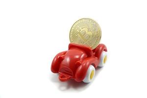 röd måla plast leksak bil bärande bitcoin guld mynt isolerat på vit foto