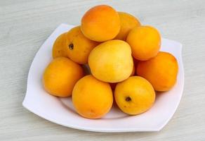 aprikoser på de tallrik och trä- bakgrund foto