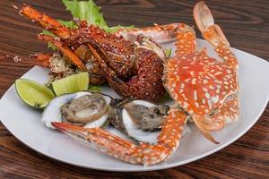 taggig hummer, krabba och ostron på de tallrik och trä- bakgrund foto