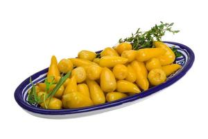gul marinerad peppar i en skål på vit bakgrund foto