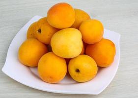 aprikoser på de tallrik och trä- bakgrund foto