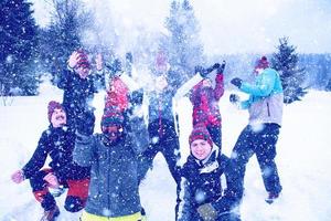 grupp av ung människor kasta snö i de luft foto