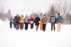 grupp av ung människor gående genom skön vinter- landskap foto