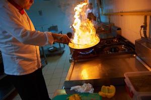 kock i hotell kök förbereda mat med brand foto