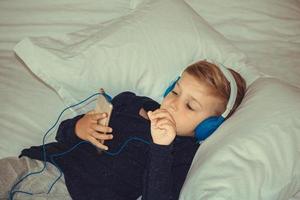 pojke med hörlurar tittar på tecknade serier på smart telefon. foto