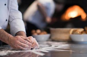 kock händer framställning deg för pizza foto