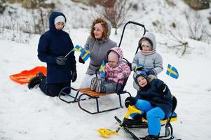 skandinavisk familj med Sveriges flagga i svenska vinterlandskap. foto