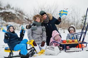 skandinavisk familj med Sveriges flagga i svenska vinterlandskap. foto