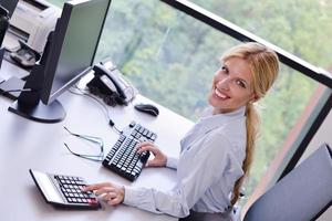 företag kvinna arbetssätt på henne skrivbord i ett kontor foto