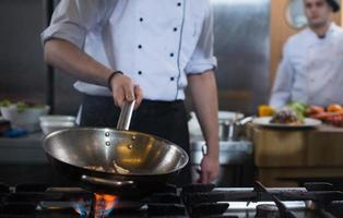 kock håller på med flambe på mat foto