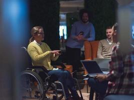 affärskvinna i rullstol har företag möte med team på modern kontor foto
