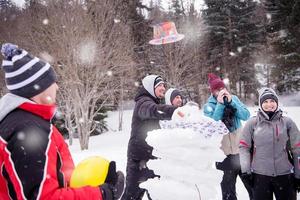 grupp av ung människor framställning en snögubbe foto