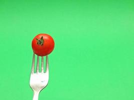 färsk tomat på gaffel med grön bakgrund foto