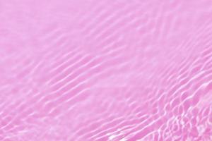 defokusering suddig transparent rosa färgad klar lugna vatten yta textur med stänk, bubbla. lysande rosa vatten krusning bakgrund. yta av vatten i simning slå samman. tropisk rosa vatten Färg flöde. foto