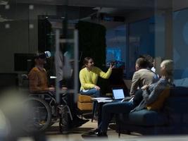 Inaktiverad affärsman i en rullstol på arbete i modern öppen Plats coworking kontor med team använder sig av virtuell verklighet googlar Drönare bistånd simulering foto