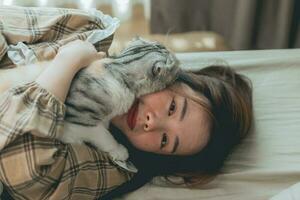 Lycklig kvinnor kramas söt katt på Hem foto