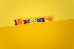 december 18 på en gul och papper bakgrund med trä- och flerfärgad brev med Plats för text. foto