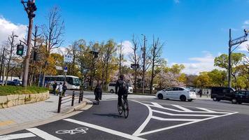Osaka, japan på april 10, 2019. situation på en fotgängare korsning, var en vit sportig bil stannar när en par ridning en cykel går över på de korsning. foto