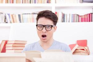 förvirrad student med glasögon omgiven av böcker foto