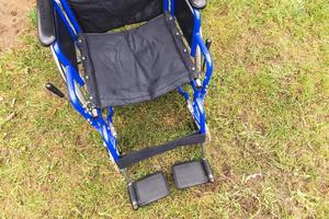 tom rullstol står i sjukhusparken och väntar på patienttjänster. rullstol för person med funktionshinder parkerad utomhus. tillgänglig för personer med funktionsnedsättning. hälso-och sjukvård medicinsk koncept. foto