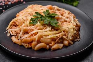 gott aptitlig klassisk italiensk pasta med tomat sås och ost på tallrik på mörk bakgrund foto