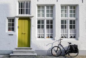 gammal tegel vägg med fönster, dörr och lutande cykel. Europa stad cykling begrepp. foto