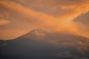 skön vulkanisk montera etna täckt med orange moln och rök under solnedgång foto