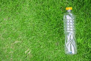 plast flaska på grön gräs bakgrund återvinna och förorening begrepp foto