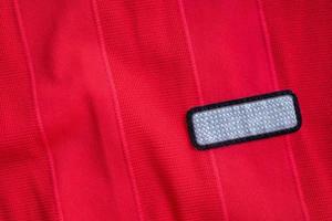 tom kläder märka märka på röd polyester sport jersey skjorta textur bakgrund foto