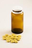 medicin flaska av brun glas med piller och tabletter. piller från flaska på de vit bakgrund. gul piller i en flaska. foto