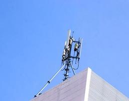 kommunikationstorn med antenner på toppen av byggnaden och ljusblå himmel bakgrund. foto