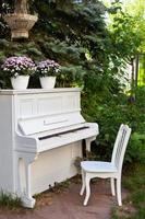 vitt piano och stolar i sommarträdgård